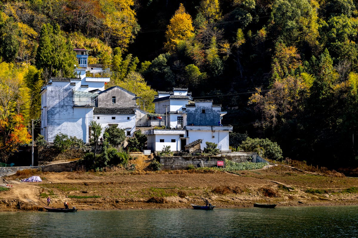 Traditional Chinese village surrounded by autumn foliage along a river - best time to visit China